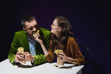Lüks Kadife giyim koyu arka plan ile masada oturan shawarma ile çift 