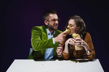 Lüks Kadife giyim koyu arka plan ile masada oturan shawarma ile çift portresi 