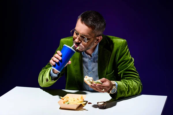 Modischer Mann Samtjacke Trinkt Limonade Während Tisch Mit Junk Food — Stockfoto