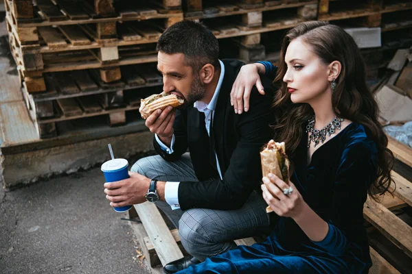 Zijaanzicht Van Paar Luxe Kleding Met Hotdogs Frisdrank Drinken Zittend — Stockfoto