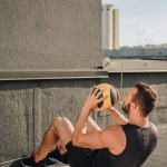 Sportsman gör sit ups med medicinboll på yogamatta på tak