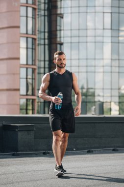 yakışıklı sporcu spor şişe su ile çatı yürüme