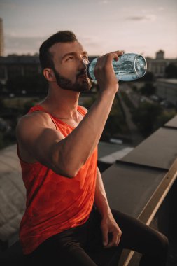 yakışıklı sporcu içme suyu spor şişe çatı üzerinde