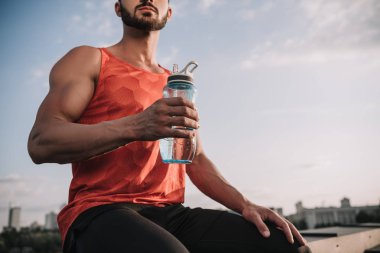 sporcu spor şişe su çatı üzerinde tutarak kırpılmış görüntü