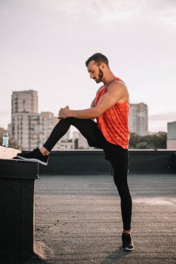 yakışıklı sporcu çatıda bacak Germe yan görünüm