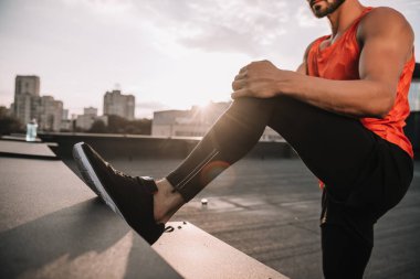 bacaklar çatıda günbatımı sırasında germe sporcu kırpılmış görüntü