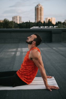 çatı kapalı gözler ile yoga mat üzerinde oturan yakışıklı adam yan görünüm