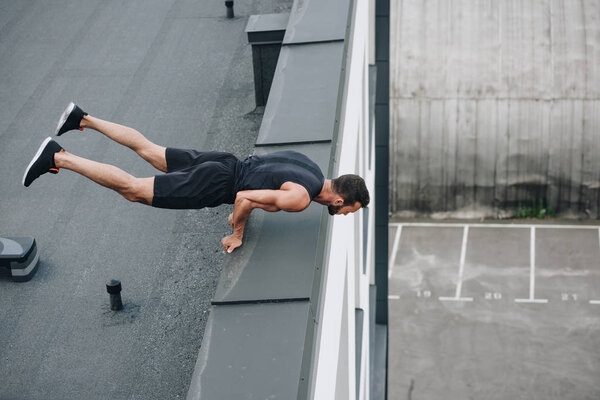 high angle view of sportsman training and standing on hands on roof 