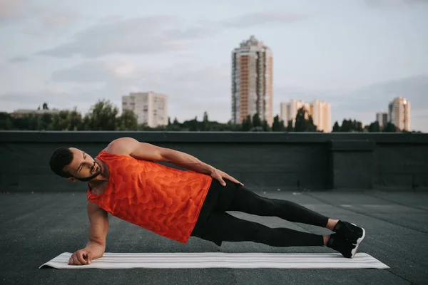 Beau Sportif Faisant Planche Latérale Sur Tapis Yoga Sur Toit — Photo