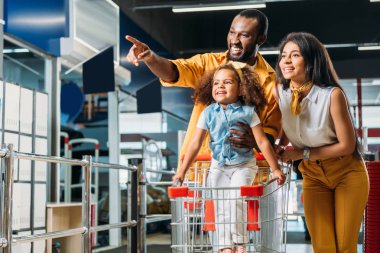 Afrika kökenli Amerikalı adam küçük kızı ve karısı süpermarkette için parmak tarafından işaret gülümseyen 
