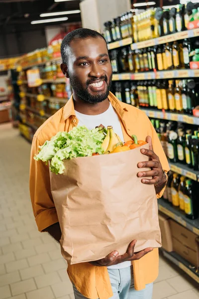 Lachende Afro Amerikaanse Mannelijke Shopper Die Papieren Tas Met Groenten — Stockfoto