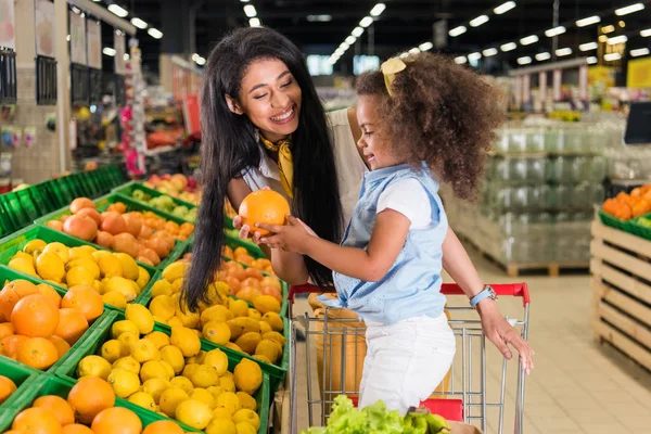 Uśmiechający Się African American Kobieta Dając Grejpfruta Córeczkę Supermarkecie — Zdjęcie stockowe