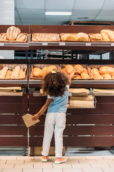 在杂货店里选择面包的小孩的后视图 — 图库照片