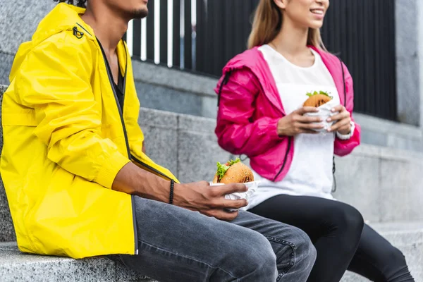 年轻夫妇在城市街吃汉堡包的裁剪图像 — 图库照片