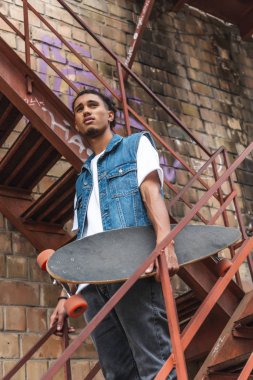 Kentsel Caddesi'nde kaykay tutan şık karışık yarış adamın düşük açılı görünüş