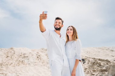 mutlu genç çift selfie çölde alarak beyaz giysili
