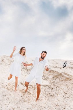 oynak genç çift alarak selfie monopod ve çölde smartphone ile
