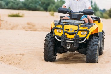 cropped shot of couple riding all-terrain vehicle on sand clipart