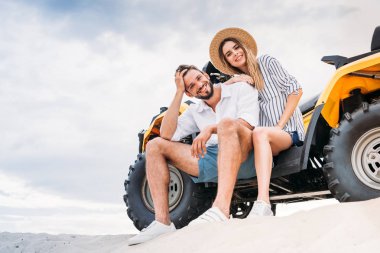 kumlu dune ATV üzerinde oturan ve kameraya bakarak güzel genç çift