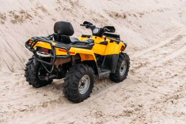 yellow all-terrain vehicle parked on sand clipart