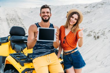 atv dijital tablet boş ekran ve başparmak ile çöl göstermek yukarıya ile güzel genç çift