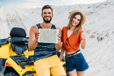 atv dijital tablet harita üzerinde ekran ve başparmak ile çöl göstermek yukarıya ile mutlu genç çift