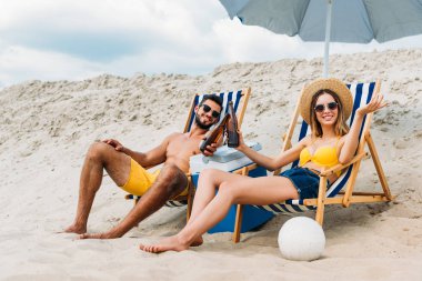 bira şişeleri kumlu plajda şezlong içinde rahatlatıcı ile güzel genç çift