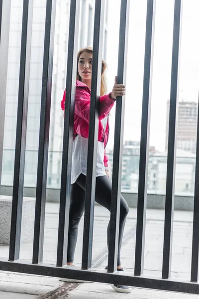 Joven Elegante Asiático Mujer Pie Cerca Metal Valla Mirando Lejos — Foto de stock gratis