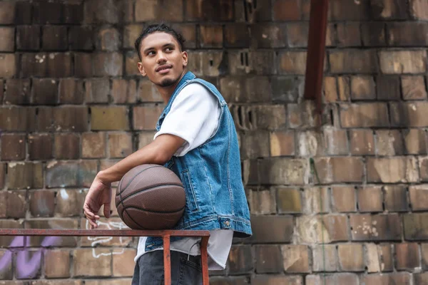 Gaya Ras Campuran Berdiri Dengan Bola Basket Dan Memandang Jauh — Foto Stok Gratis