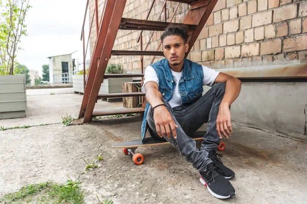 Young Stylish Mixed Race Man Sitting Skateboard Looking Camera Urban — Free Stock Photo