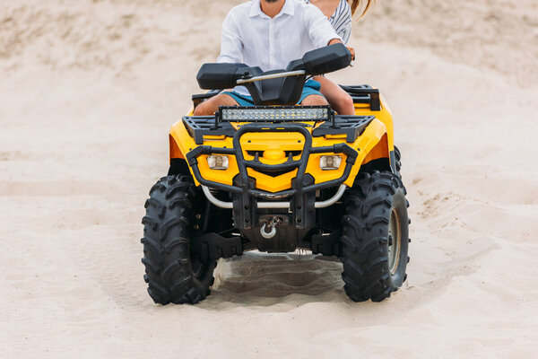 cropped shot of active young couple riding all-terrain vehicle in desert