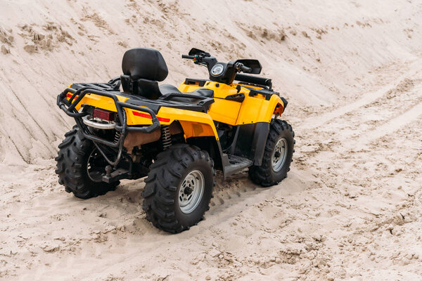 yellow all-terrain vehicle parked on sand