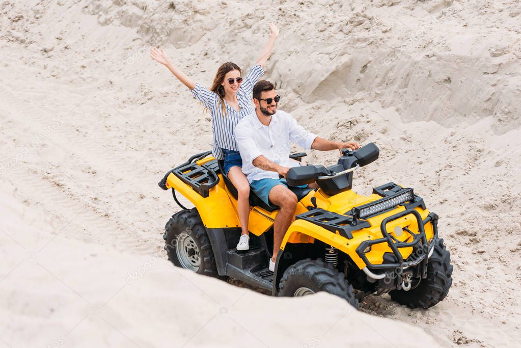 high angle view of happy young couple riding ATV in desert