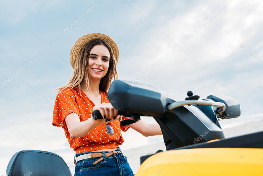 beautiful young woman sitting on all-terrain vehicle and looking at camera