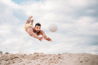 plaj voleybolu oynarken top için atlama yakışıklı genç