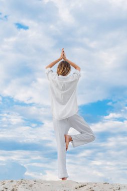 pratik yoga ağaç poz kumul üzerinde duran güzel genç kadın