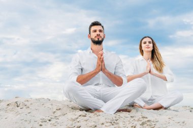 lotus poz (padmasana kabuklarıyla kumlu otururken pratik yoga güzel genç çift)