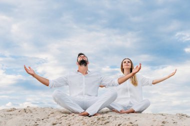 lotus poz (padmasana kabuklarıyla kumlu otururken meditasyon yogi üzerinde genç çift)