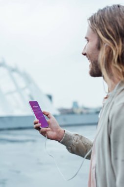 mutlu genç adam sokakta ekranda instagram app ile Smartphone kullanarak