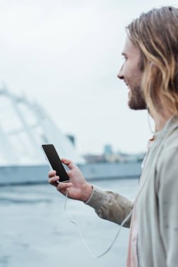 yakışıklı genç adam sokakta boş ekran ile Smartphone kullanarak