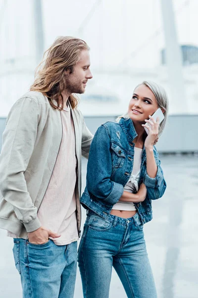 Красивый Молодой Человек Смотрит Свою Девушку Пока Разговаривает Телефону — стоковое фото