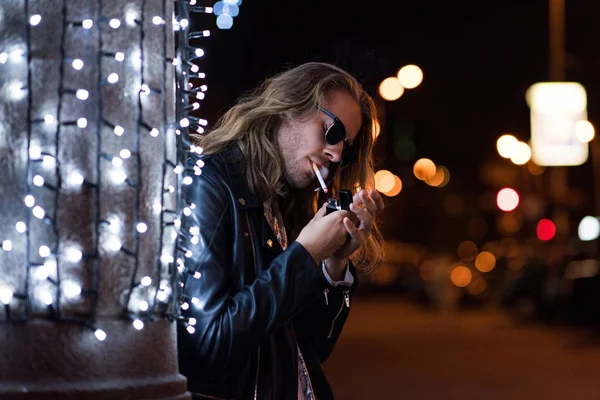 Joven Guapo Gafas Sol Chaqueta Cuero Fumar Cigarrillo Bajo Guirnalda — Foto de Stock