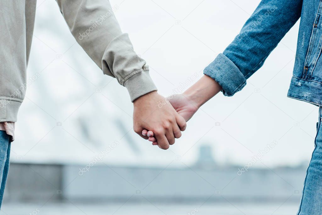 cropped shot of couple holding hands on street on cloudy day