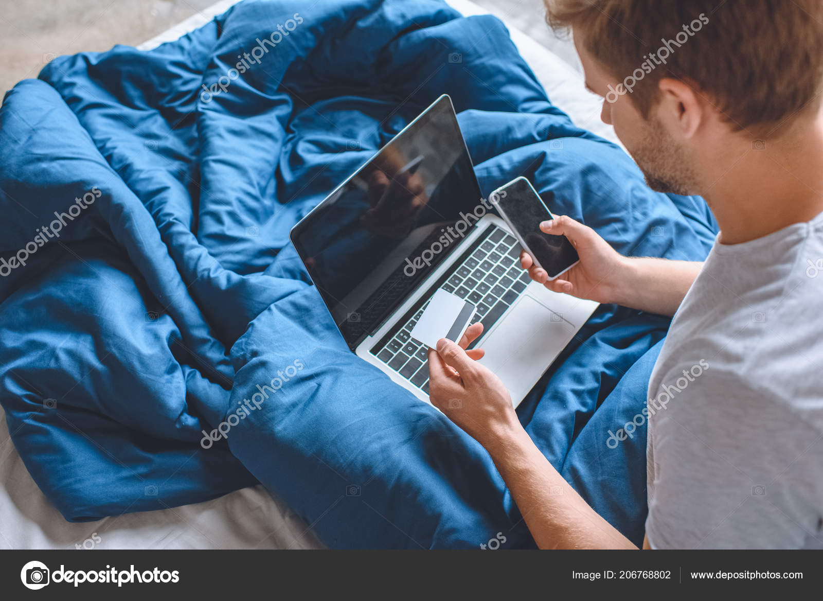 Young Man Bed Credit Card Laptop Doing Online Shopping Smartphone