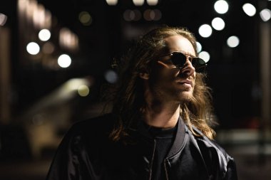 yakın çekim güneş gözlüğü ve deri ceket şehir geceleri sokak üzerinde çekici bir genç adam portresi