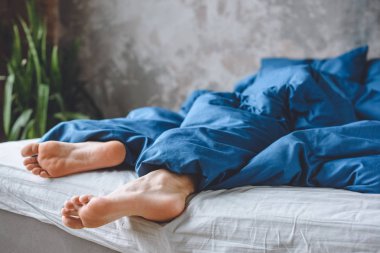 mens bacaklar evde yatakta battaniyenin altında uyku resim kırpılmış