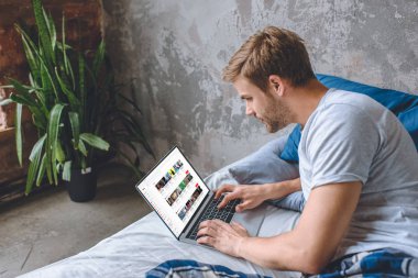yakışıklı genç adam yatakta dizüstü ekran youtube ile kullanma