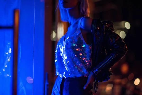 迷人的年轻女子在夜间在街道上的蓝色灯光下的闪亮的坦克 — 图库照片