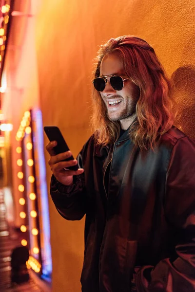 Gelukkig Jonge Man Leren Jas Zonnebril Met Smartphone Straat Nachts — Stockfoto