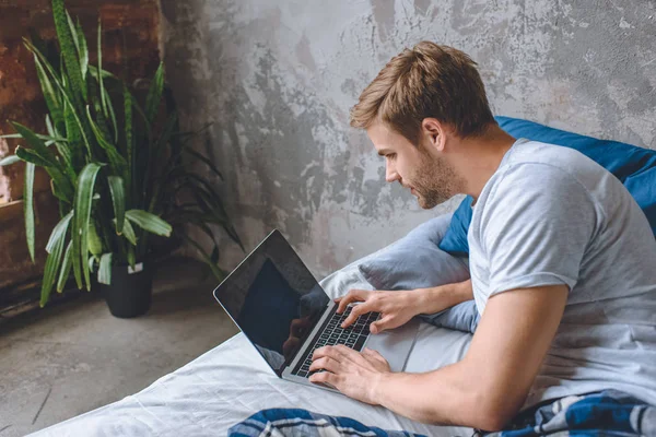 Przystojny Młody Mężczyzna Łóżku Laptop Pomocą Strony Internetowej Rezerwacji Ekranie — Zdjęcie stockowe